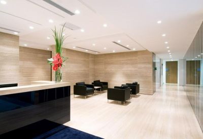 Minimalist reception lobby with a dark front desk and a modern floral arrangement.