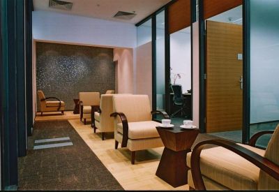 Quiet lounge area with cream-colored armchairs, small side tables, and a textured feature wall.