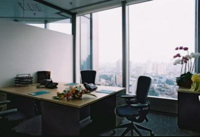 Private executive office with a wooden desk, flowers, and large windows overlooking the city.