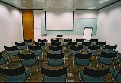 Training room set up in a classroom style with blue chairs and a large projection screen.