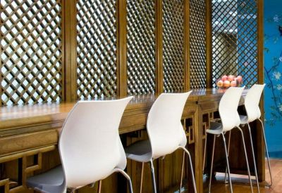 Breakout area with white bar stools and a wooden lattice partition.