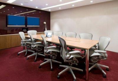 Large boardroom featuring a long wooden table and multiple ergonomic chairs.