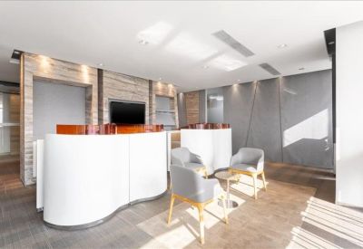Breakout lounge with curved white counters, grey armchairs, and wood accents.