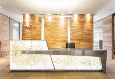 Sleek modern reception area featuring a backlit stone desk and wood paneled wall.