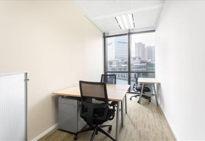 Small private office with two desks and a city view through large windows.