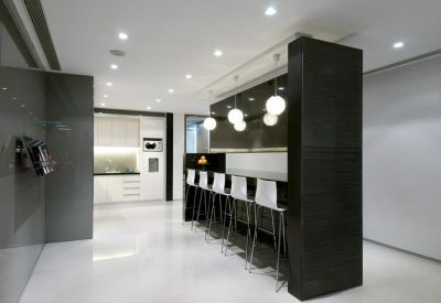 Modern office breakroom with a sleek black breakfast bar and white stools.