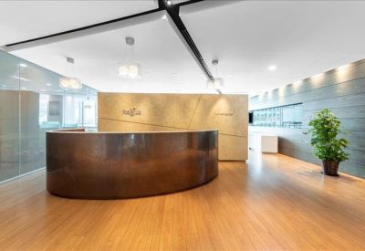 Reception area featuring a curved bronze-tone front desk and warm wood flooring.