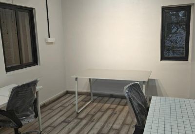 Private workstations with sleek black pendant lighting and a wall fan.