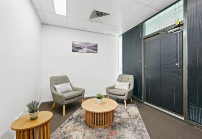 Small consultation room with two grey armchairs and a circular coffee table.
