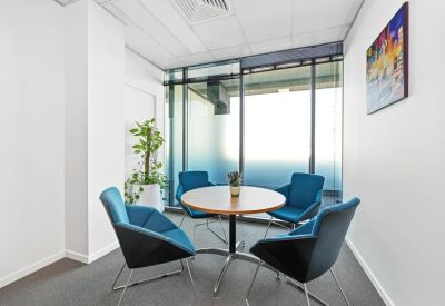 Small meeting room with four blue chairs around a circular wooden table.
