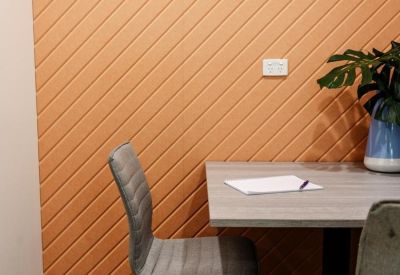 Quiet focus area with a grey armchair and an orange-toned geometric patterned feature wall.