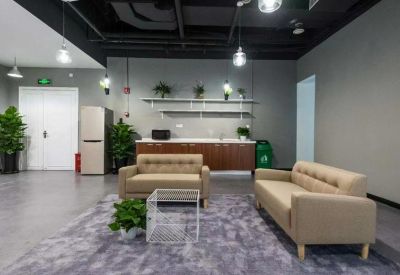 Comfortable lounge area with beige sofas, a grey rug, and a small kitchenette.
