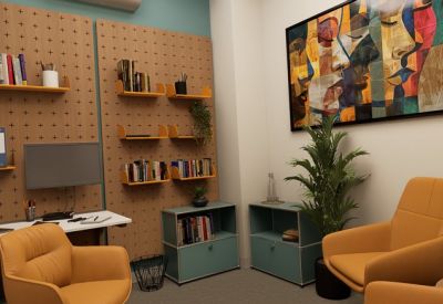 Small meeting area with orange armchairs, teal cabinets, and abstract wall art.