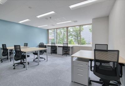 Spacious office layout featuring white desks and a soft blue accent wall.