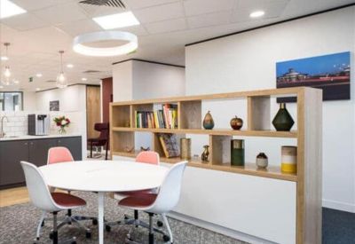 Lounge area with a round white table, colorful chairs, and a light wood shelving unit.