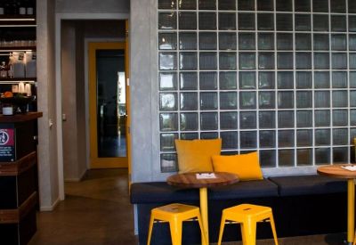 Small cafe-style seating area with yellow stools and a glass block wall.