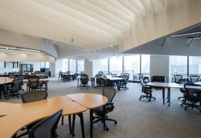 Open-plan office area with rows of desks and white acoustic ceiling fins.