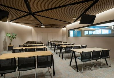 Meeting room with tiered wooden ceiling and long rows of desks.