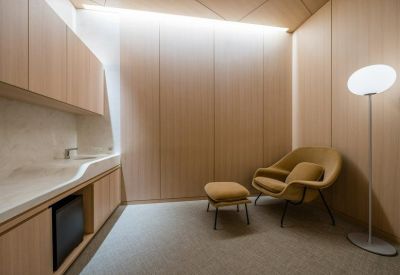 Private nursing or wellness room with a yellow armchair, footstool, and sink.