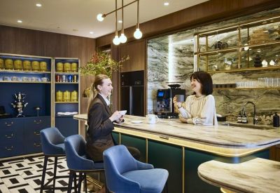 Elegant cafe and kitchen area with marble counters and blue bar stools.