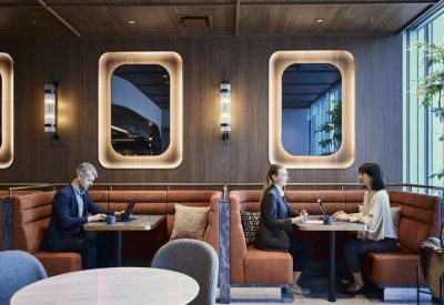 Wood-paneled breakout area with comfortable leather booths and stylish wall sconces.