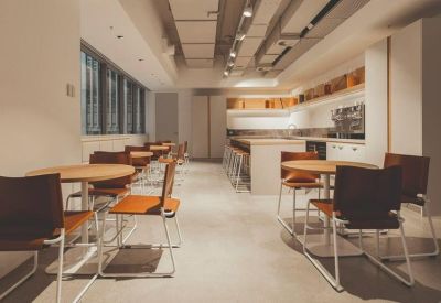 Modern communal kitchen and cafe area with wooden tables and industrial lighting.
