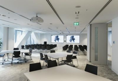 Versatile coworking space with white tables, black chairs, and digital displays.