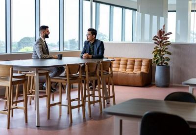 Lounge area featuring a long high-top table and a leather sofa near large windows.