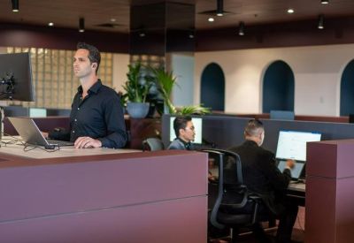 Modern open-plan workspace with dark plum partitions and employees at computer workstations.
