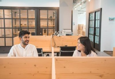 Modern office workspace with wooden desk partitions and glass doors.