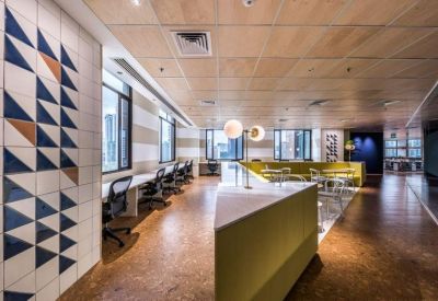Communal workspace with a yellow banquette and patterned tile feature wall.