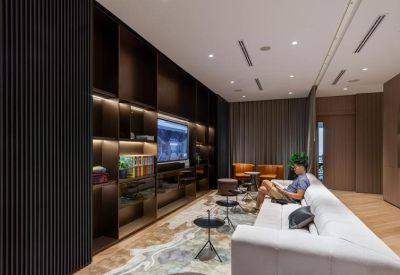 Sophisticated lounge with a long white sofa, dark wood shelving, and warm ambient lighting.