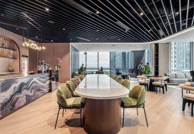 Spacious communal dining area featuring a long marble table and green velvet chairs.