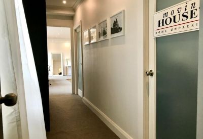 Well-lit hallway with framed artwork and frosted glass doors.