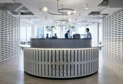 Round reception desk with a white slatted base and modern ring pendant lighting.