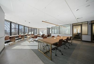 Open-plan workspace with long timber desks and panoramic views of neighboring skyscrapers.
