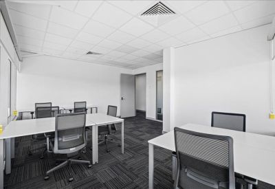 Spacious open-plan workspace with multiple white desks and ergonomic mesh chairs.
