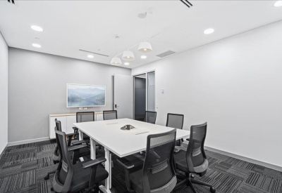 Professional meeting room with a large white table, seating for six, and a wall-mounted screen.