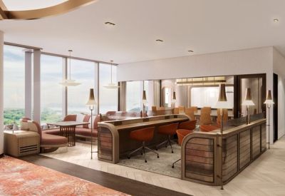 Modern coworking area with orange swivel chairs at a long wooden counter beside large windows.