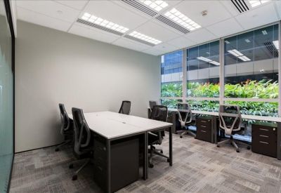Bright private office with a long white desk and large windows overlooking greenery.