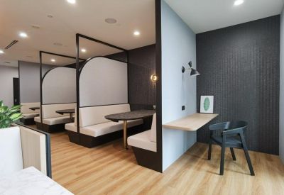 Modern semi-private workspace booths with wood floors and a dedicated desk nook.