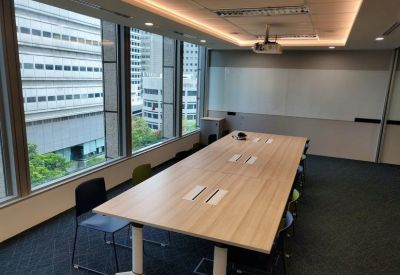 Bright conference room with a long wooden table, city views, and ceiling-mounted projector.