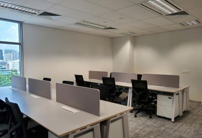 Open-plan workspace with white desks, grey privacy screens, and black ergonomic chairs.