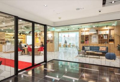 Bright glass-walled coworking space with red chairs and a blue lounge area.