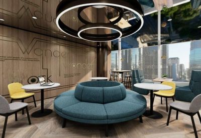 Communal breakout space with a central teal circular sofa, yellow accent chairs, and city views.