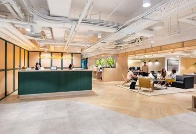 Bright reception area featuring a deep green front desk and open-plan lounge seating.