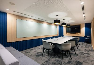 Professional meeting room featuring deep blue acoustic walls, a long white table, and grey seating.
