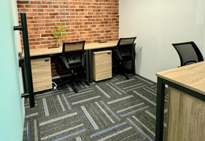 Private office featuring a brick accent wall and two workstations with wooden desks.