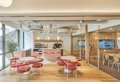 Bright breakout area with red chairs, round tables, and a bar counter.