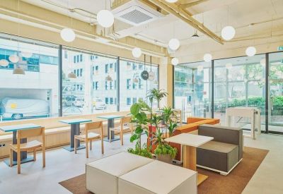 Bright break area featuring potted plants, cushioned seating, and views of the city.
